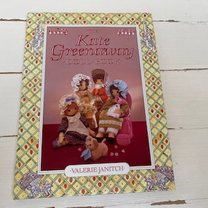 May include: The Kate Greenaway Doll Book by Valerie Janitch. A book cover with a yellow and red checkered border. The cover features an illustration of four dolls dressed in vintage clothing.