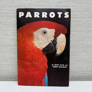 May include: A book titled "Parrots" with a red and blue parrot on the cover. The book is by Henry Bates and Robert Busenbark.