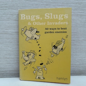 May include: A vintage book titled "Bugs, Slugs & Other Invaders" with illustrations of cartoon airplanes. The book cover is yellow with black and white drawings and text. The book promises "50 ways to beat garden enemies."