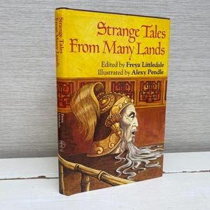 May include: A yellow book cover with the title "Strange Tales From Many Lands" and the names of the editor and illustrator. The cover features an illustration of a person with a long, flowing beard and a golden headdress.