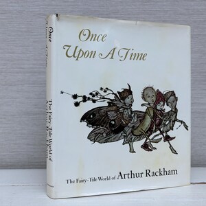 May include: A vintage book titled "Once Upon A Time" with a cream-colored cover. The cover features an illustration of whimsical figures and the text "The Fairy-Tale World of Arthur Rackham".