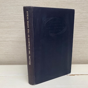 May include: A dark blue hardback book with gold lettering on the spine that reads "PHILLIPS: THE DYNAMICS OF THE UPPER OCEAN".
