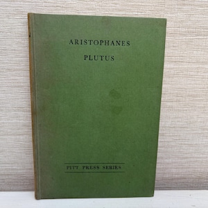 Può includere: Un libro d'epoca con una copertina verde intitolato "ARISTOFANE PLUTUS". La copertina del libro presenta anche il testo "PITT PRESS SERIES" in nero. Il libro ha un aspetto usurato, che suggerisce età e utilizzo.