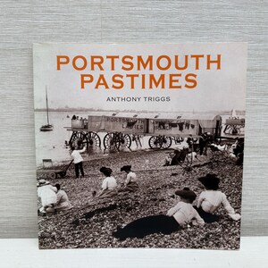 May include: Book cover titled "Portsmouth Pastimes" by Anthony Triggs. The image is a vintage black and white photograph of people on a beach with a large wagon and a sailboat in the background. The text is in orange.