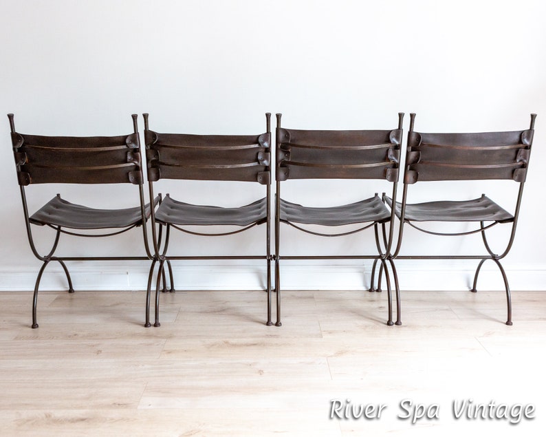May include: Four brown leather-backed chairs with metal frames. The chairs are arranged in a row, facing forward. The chairs have a simple, rustic design.