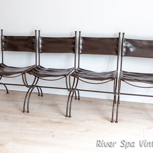 May include: Four brown leather chairs with metal frames. The chairs are arranged in a row and have a simple, rustic design.