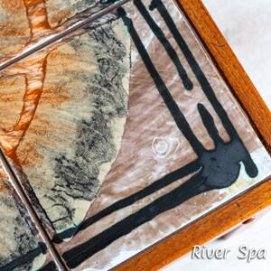 May include: A vintage coffee table with a tiled top. The tiles are brown, white, and black with abstract designs. The table has a wooden frame.