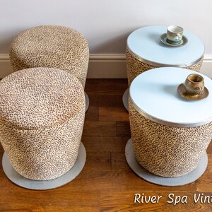 May include: Four small, round, leopard print ottomans with white tops. Two of the ottomans have a white top with a light blue rim and a small saucer with a teacup on top.  The text "River Spa Vintage" is at the bottom of the image.