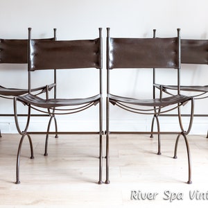 May include: Four brown leather chairs with metal frames. The chairs are arranged in a row, facing the camera. The chairs have a simple, rustic design.
