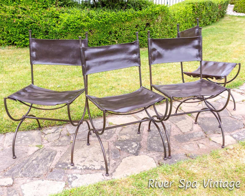 May include: Four brown leather chairs with metal frames. The chairs are arranged in a row on a stone patio. The chairs are made of a dark metal and have a simple design.
