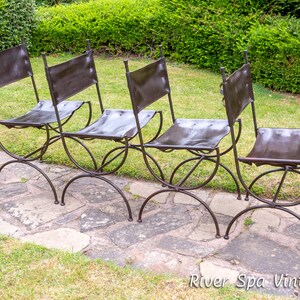 May include: Four black metal chairs with brown leather seats. The chairs are arranged in a row on a stone patio.