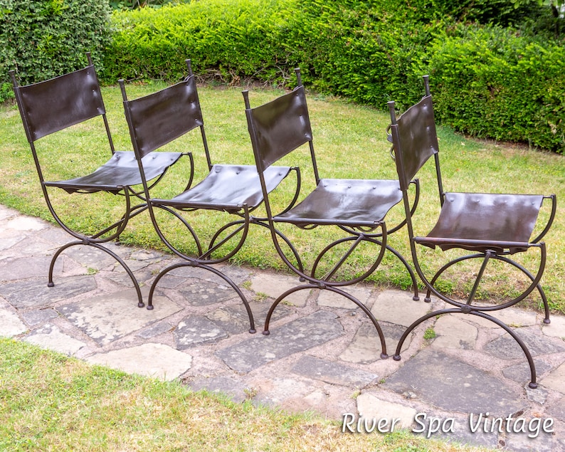May include: Four black metal chairs with brown leather seats. The chairs are arranged in a row on a stone patio.