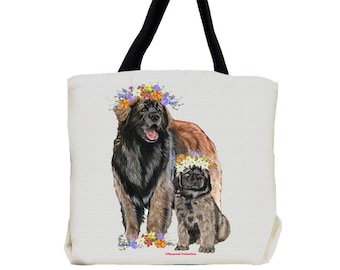 Op de afbeelding: Een witte canvas tote bag met zwarte handvatten heeft een afbeelding van twee Berner Sennenhunden die bloemenkransen dragen. De grotere hond staat en de kleinere hond zit. De honden zijn omringd door bloemen.