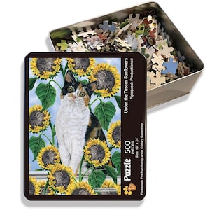 May include: A 500-piece jigsaw puzzle in a tin box featuring a calico cat sitting amongst a field of sunflowers. The puzzle is titled "Under the Tuscan Sunflowers" and is by artist Mary Badenhop.