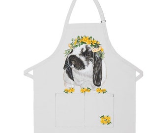 May include: White apron with a black and white bunny wearing a yellow flower crown. The bunny is in the center of the apron and there are yellow flowers on the bottom of the apron.