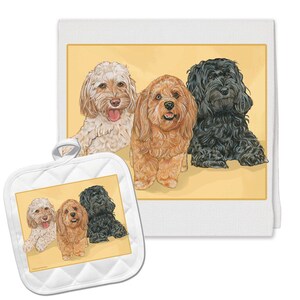 May include: A set of three kitchen towels featuring a colorful illustration of three doodle dogs. The dogs are a cream, brown, and black doodle. The towels are white with a yellow background.