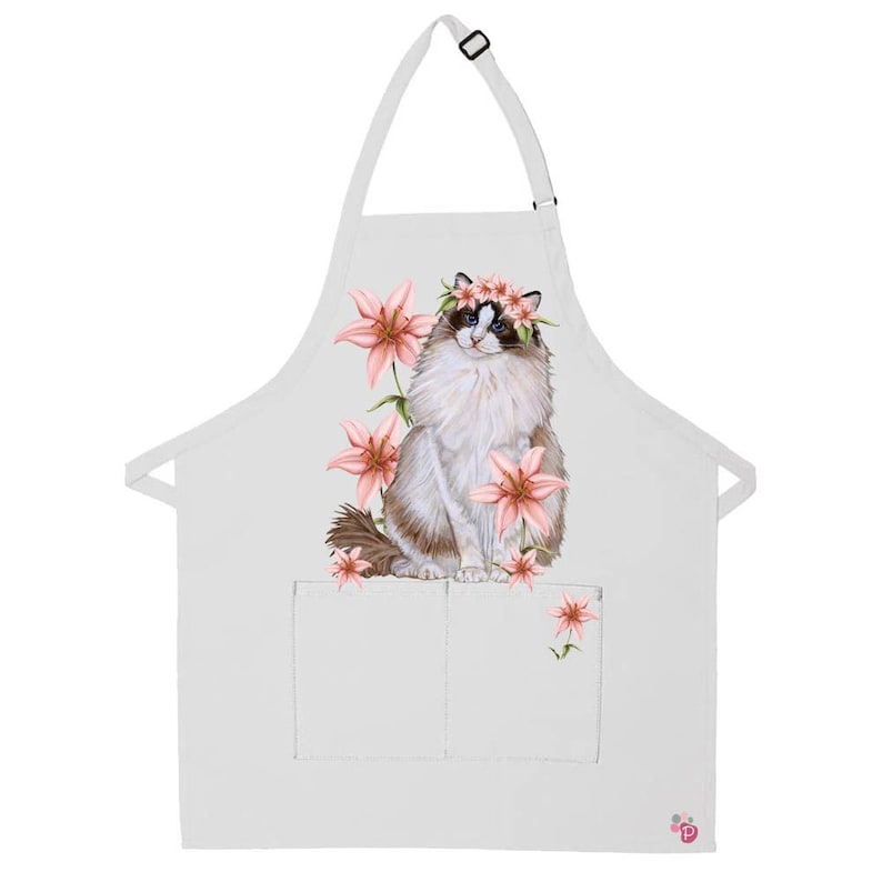 Puede incluir: Delantal de cocina blanco con un bolsillo que presenta una ilustraci&oacute;n de acuarela de un gato Ragdoll con una corona de flores rosas y rodeado de lirios rosas.
