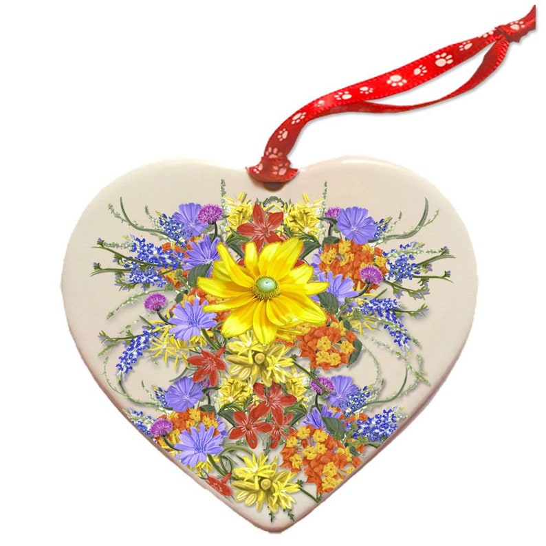 Op de afbeelding: Een hartvormige keramische ornament met een kleurrijk boeket wilde bloemen, waaronder gele, rode, oranje, paarse en blauwe bloemen.