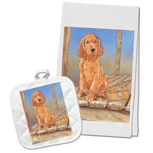May include: A set of kitchen towels and a pot holder featuring a red Irish Setter puppy sitting on a wooden dock with a fishing rod and a wicker fishing basket. The puppy is looking at the camera with a curious expression.