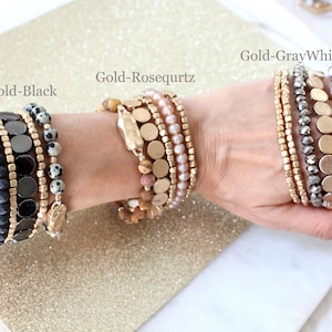 May include: Three sets of layered bracelets with different colored beads and gold accents. The bracelets are labeled "Gold-Black", "Gold-Rosequartz", and "Gold-GrayWhite".