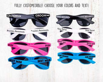 May include: A set of eight sunglasses with different colored frames and text printed on the lenses. The text includes "Groom", "Bride", "Best Man", "Ring Security", "Petal Patrol", "Flower Girl", and "Ring Bearer".