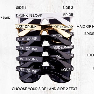 Op de afbeelding: Een stapel zwarte en witte zonnebrillen met verschillende tekst aan elke kant. De tekst omvat "Drunk in Love", "Just Drunk", "Bride", "Maid of Honor", "Bridesmaid", "I Do Crew" en "Squad".