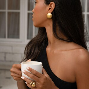a model wearing a 18k gold plated large earrings