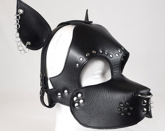 May include: Black leather dog mask with silver studs and a metal ring on the nose. The mask has two floppy ears with silver chains attached.