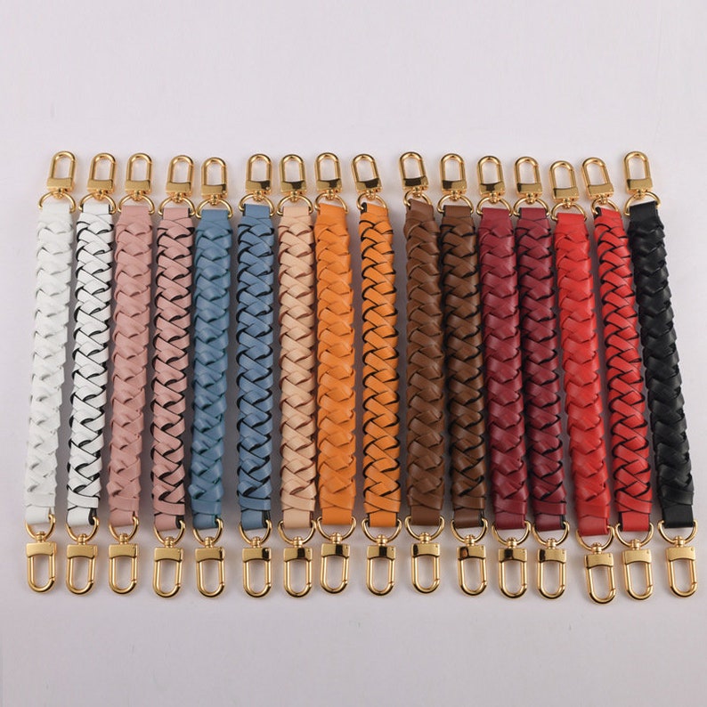 May include: A set of 15 braided leather straps with gold-toned clasps. The straps are in various colors, including white, pink, blue, beige, orange, brown, red, and black.