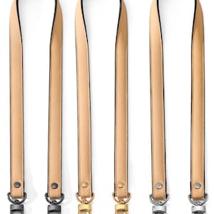 May include: Four beige leather bag straps with black edging and metal hardware. Two straps have silver-tone clasps, and two have gold-tone clasps. The straps are vertically aligned against a white background.