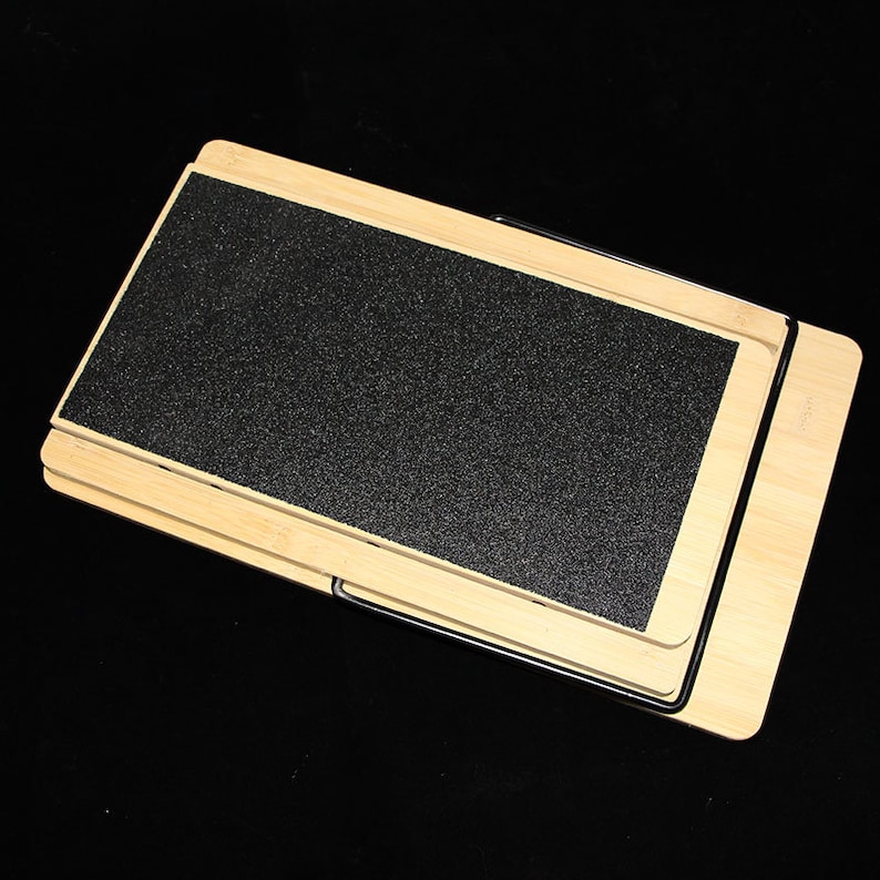 May include: A wooden pet ramp with a black, textured surface. The ramp is made of light-coloured wood and has a foldable design. The ramp is designed to help pets access elevated surfaces.