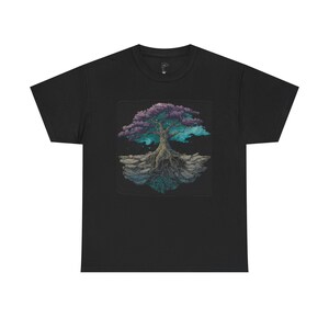 Könnte beinhalten: Schwarzes T-Shirt mit einem detaillierten Grafikdesign eines Baumes mit lila und türkisem Laub und freiliegenden Wurzeln. Der Baum ist vor einem dunklen Hintergrund platziert, was einen auffälligen Kontrast erzeugt. Das Design ist auf dem Shirt zentriert.