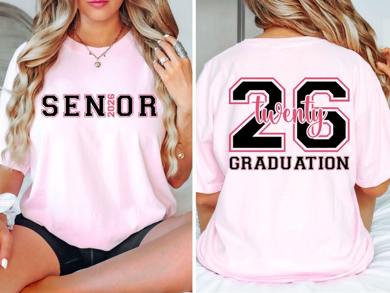May include: Light pink t-shirt with black and pink text. The front of the shirt says "SENIOR 2026". The back of the shirt has a large "26" with "Twenty" in the middle and "GRADUATION" below.