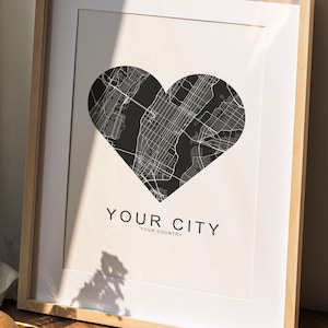 Könnte beinhalten: Ein gerahmter Druck einer Stadtkarte in Herzform. Der Text unter der Karte lautet "YOUR CITY YOUR COUNTRY".