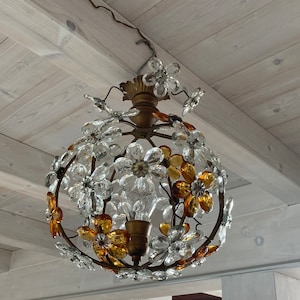 May include: A round chandelier with a gold metal frame and clear and amber glass flower accents.