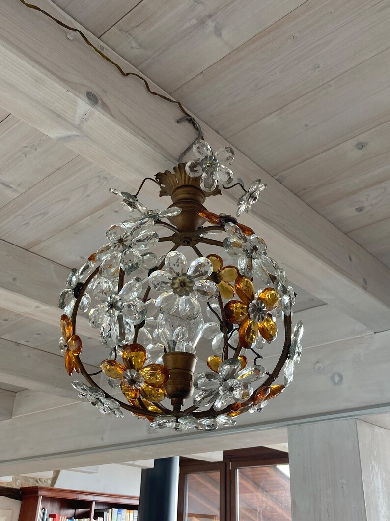 May include: A round chandelier with a gold metal frame and clear and amber glass flower accents.