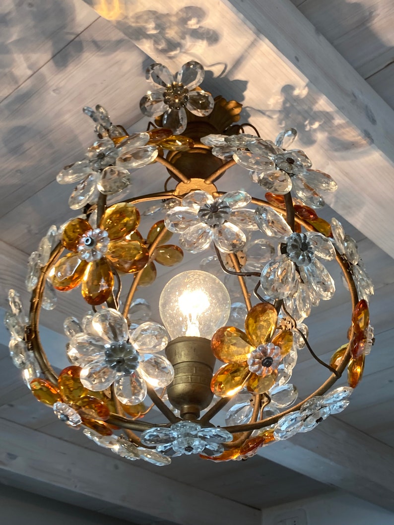 May include: A gold metal chandelier with clear and amber glass flower-shaped accents. The chandelier has a single light bulb in the center.