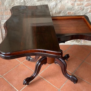 Op de afbeelding: Een donkerhouten tafel met een uitklapbare blad en gesneden poten. De tafel heeft een rijke, donkerbruine afwerking en ingewikkelde details.