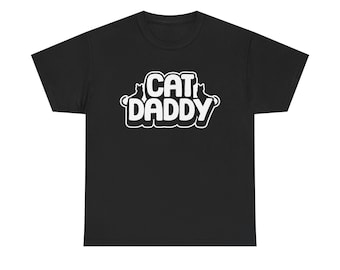 Op de afbeelding: Een zwart t-shirt met korte mouwen en de witte tekst CAT DADDY in een vet, afgerond lettertype op de borst. Het ontwerp bevat twee kleine silhouetten van katten aan weerszijden van het woord CAT, wat een grafische afbeelding op het shirt vormt.