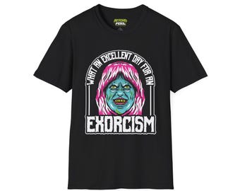 May include: A black short-sleeve t-shirt featuring a graphic of a teal-skinned face with pink hair and yellow teeth. The text above the face reads "WHAT AN EXCELLENT DAY FOR AN" and the text below reads "EXCORCISM" in a bold, white, distressed font.