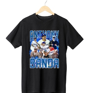 Pu&ograve; includere: T-shirt nero con un design blu e bianco con la scritta "ANTHONY BANDA" e immagini di giocatori di baseball. La grafica include pi&ugrave; immagini di giocatori, creando un design dinamico e accattivante.