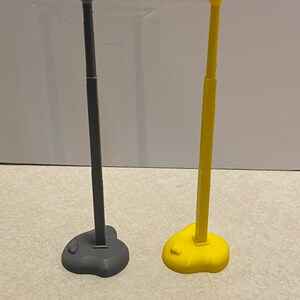 May include: Two 3D printed flagpoles, one gray and one yellow, with rounded tops and heart-shaped bases.
