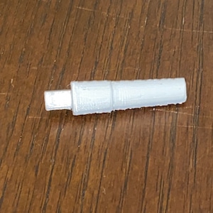 May include: A white plastic connector with a small, rectangular opening on one end.