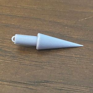 May include: A gray plastic cone-shaped object with a loop at the top. The object is about 3 inches long.