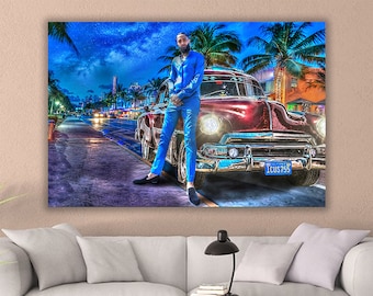 May include: A man in a blue suit stands next to a vintage red car with a California license plate that reads "1CUS755". The car is parked on a street with palm trees and a city skyline in the background.