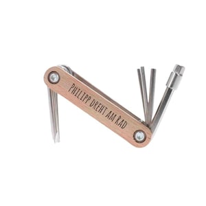 Könnte beinhalten: Ein Holz-Multitool mit silberner Oberfläche und einer personalisierten Gravur mit dem Text "Philipp dreht am Rad".