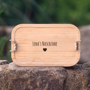 Könnte beinhalten: Eine Holzlunchbox mit einem Herzen und dem Text "Lena's Naschzone" auf der Vorderseite.