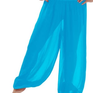 Könnte beinhalten: Haremshose in leuchtendem Türkis. Diese locker sitzende Hose hat einen gerafften, elastischen Bund und eine entspannte, fließende Silhouette. Der Stoff wirkt leicht und halbtransparent, ideal für warmes Wetter oder Tanz. Die Hose ist in einem leuchtenden Blauton gehalten.