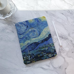 May include: A blue and yellow iPad case with a painting of a starry night sky and a small town. The case has a textured surface and a white border.
