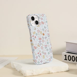 May include: A light blue phone case with a cute pattern of flowers, animals, and moons. The case is made of a soft, flexible material and has a raised lip around the camera lens to protect it from scratches.